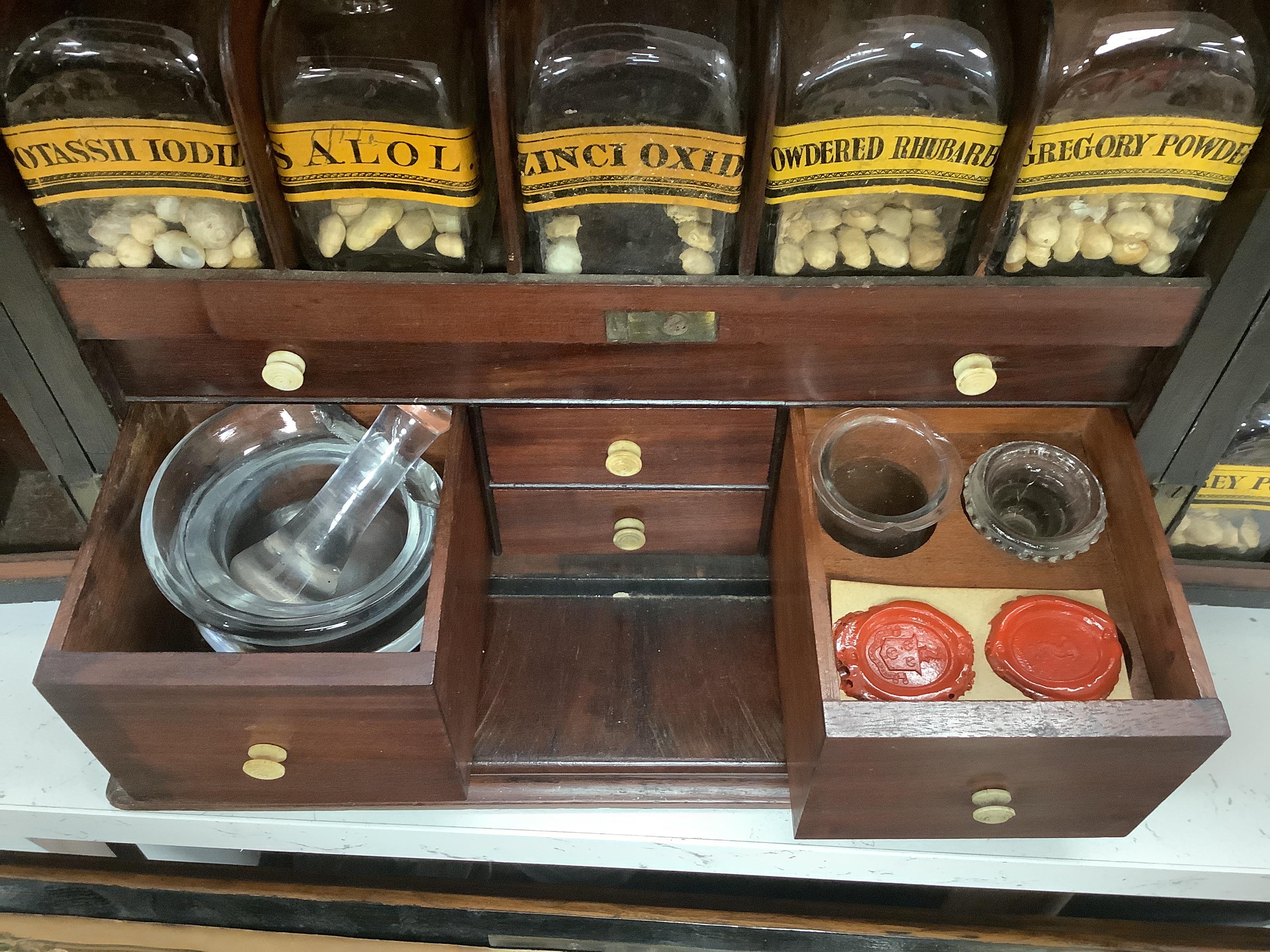 A Georgian mahogany domestic medicine chest, with bone drawer knobs and escutcheons, containing a number of glass square section drug bottles, fitted drawers containing scales, a pestle and mortar, etc., 29cm wide, 25cm